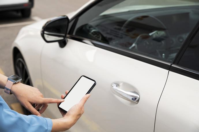 Smartphone in der Hand einer Person vor einem Auto