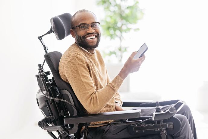 Mann im Rollstugl mit Smartphone in der Hand