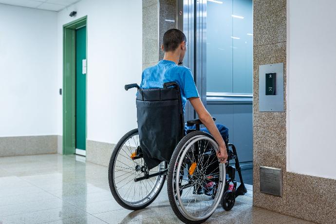 Mann im Rollstuhl vor dem offenen Lift