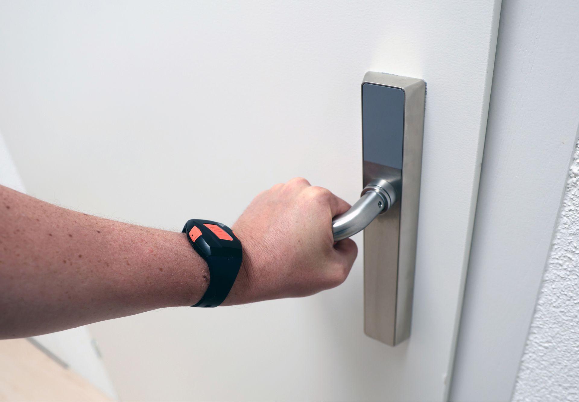 Hand auf Türfalle mit SmartLiberty Bewohnerbadge am Handgelenk